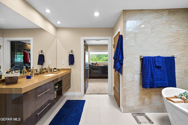 full bathroom with baseboards, tile patterned floors, vanity, a freestanding tub, and recessed lighting