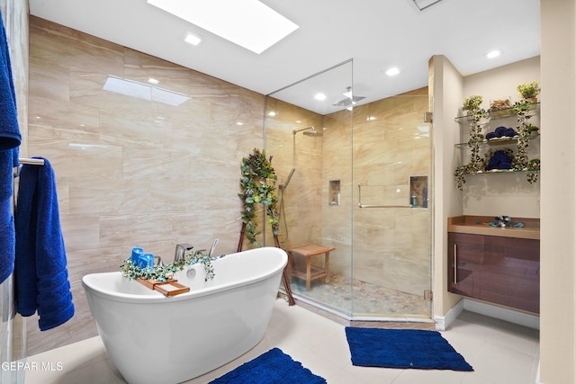 full bathroom featuring a skylight, tile patterned floors, a freestanding tub, a shower stall, and tile walls