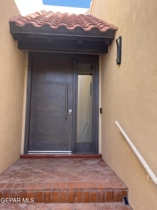 entrance to property featuring stucco siding and a tiled roof