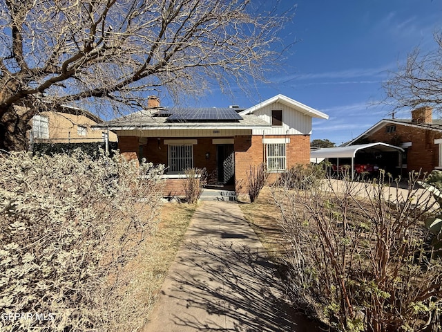 view of front of house featuring roof mounted solar panels and brick siding