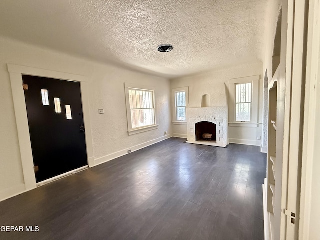 unfurnished living room featuring a textured ceiling, a textured wall, a fireplace, visible vents, and dark wood finished floors