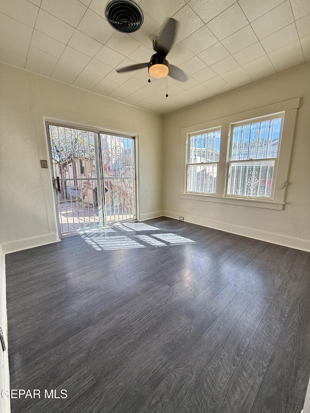 spare room featuring dark wood-type flooring, a healthy amount of sunlight, visible vents, and baseboards