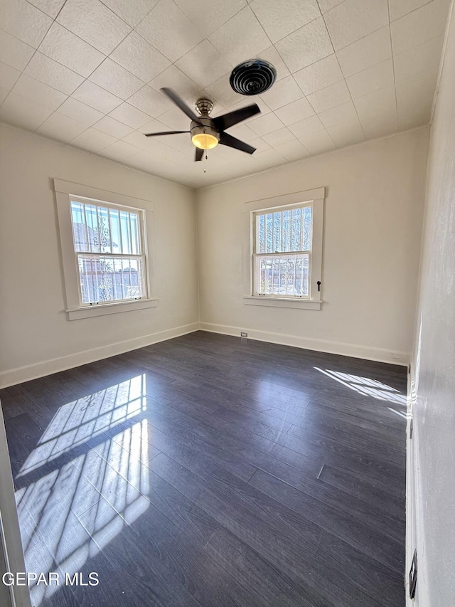 spare room with baseboards, visible vents, dark wood finished floors, and a wealth of natural light