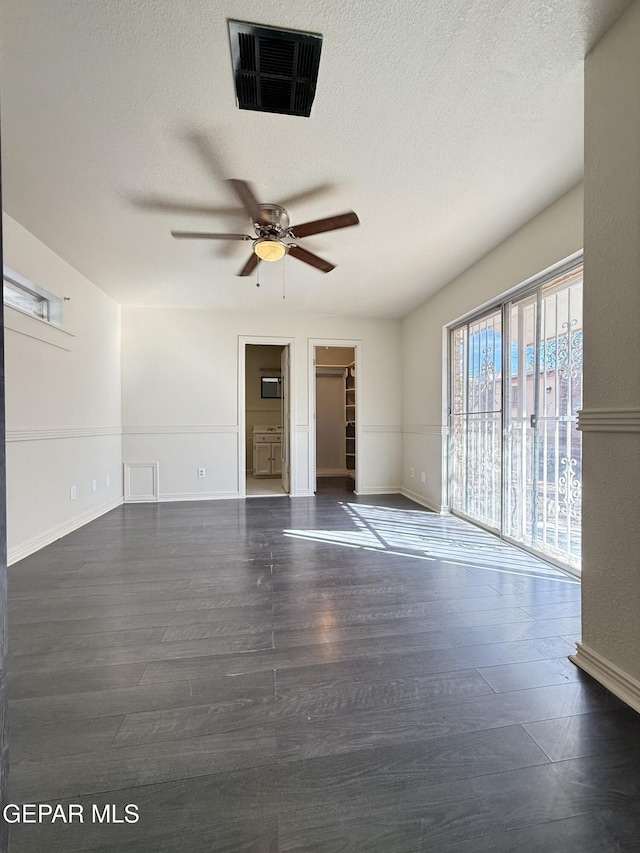 spare room featuring a textured ceiling, dark wood finished floors, visible vents, and a ceiling fan