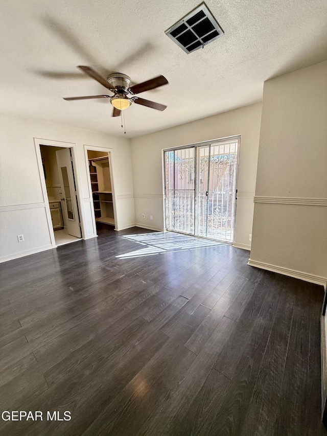 unfurnished room with baseboards, visible vents, ceiling fan, wood finished floors, and a textured ceiling