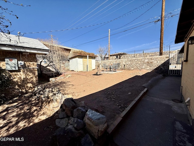 view of yard with a gate, a fenced backyard, an outdoor structure, and a shed