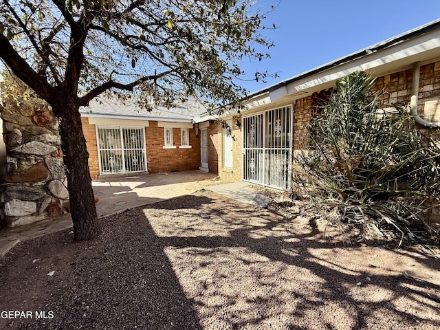 rear view of property with brick siding and a patio