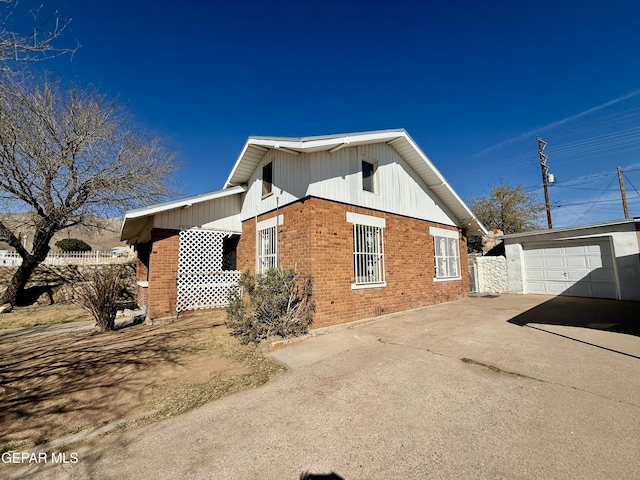 view of side of property featuring a garage, brick siding, an outdoor structure, fence, and concrete driveway