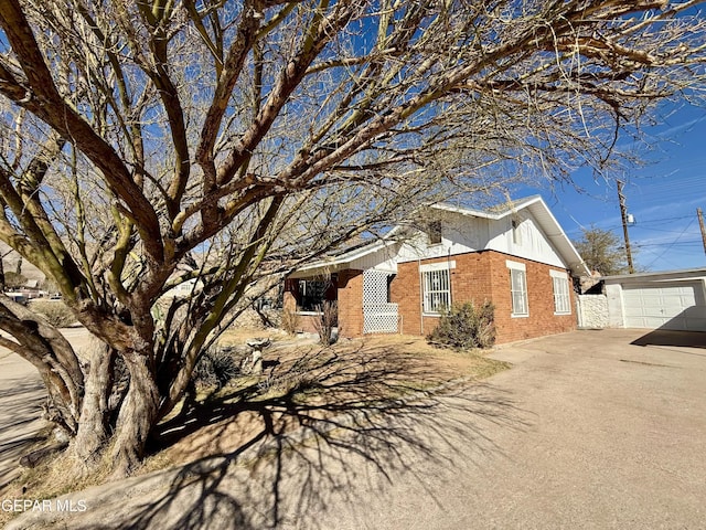 single story home with an outbuilding, brick siding, driveway, and an attached garage