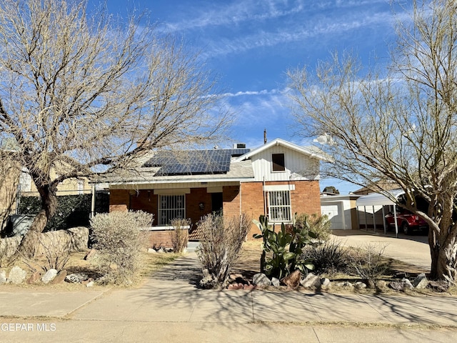 view of front of property with a garage, solar panels, brick siding, and concrete driveway