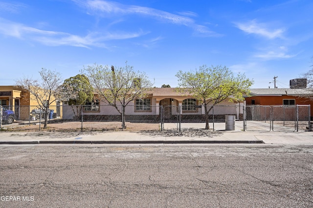 view of front of property with a fenced front yard, stucco siding, and a gate