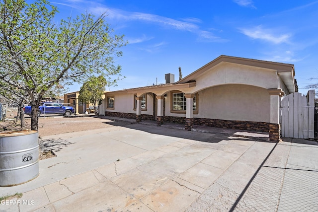 ranch-style home with stucco siding, driveway, and a gate