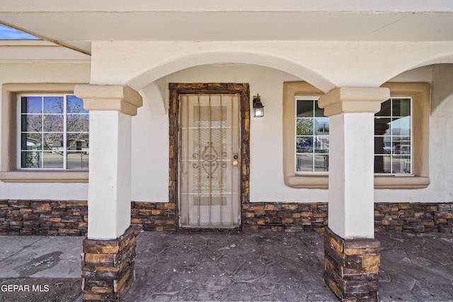 property entrance with stone siding and stucco siding