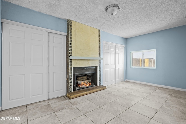 unfurnished living room featuring tile patterned flooring, a fireplace, baseboards, and a textured ceiling