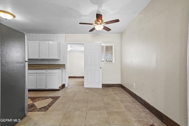 kitchen featuring backsplash, dark countertops, light tile patterned flooring, baseboards, and ceiling fan