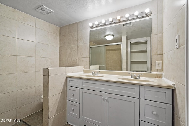 bathroom featuring a sink, visible vents, tile walls, and a shower stall