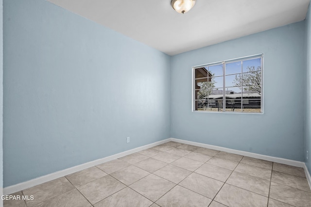 empty room with light tile patterned floors and baseboards