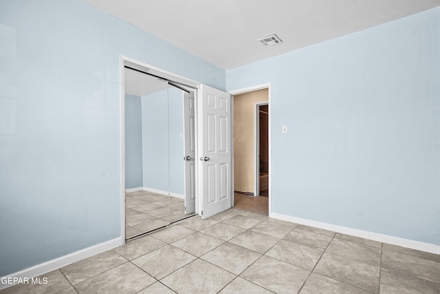 unfurnished bedroom featuring light tile patterned floors, visible vents, baseboards, and a closet