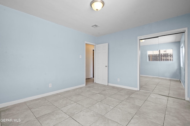 unfurnished bedroom with light tile patterned floors, visible vents, baseboards, and a closet