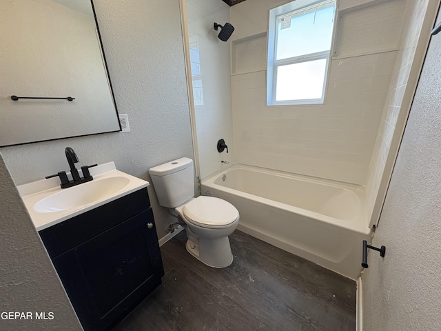 bathroom featuring shower / washtub combination, a textured wall, toilet, vanity, and wood finished floors