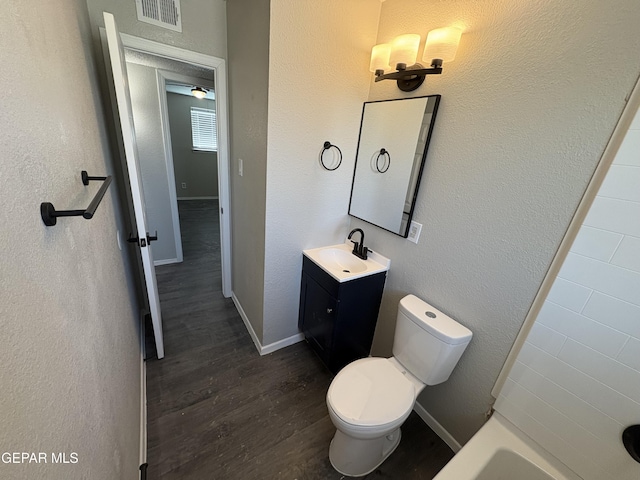 bathroom with baseboards, visible vents, toilet, wood finished floors, and vanity