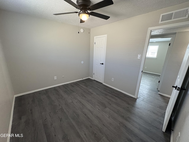 spare room with visible vents, dark wood-type flooring, a ceiling fan, a textured ceiling, and baseboards