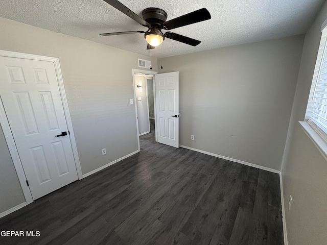 unfurnished bedroom with dark wood-style floors, a textured ceiling, visible vents, and baseboards