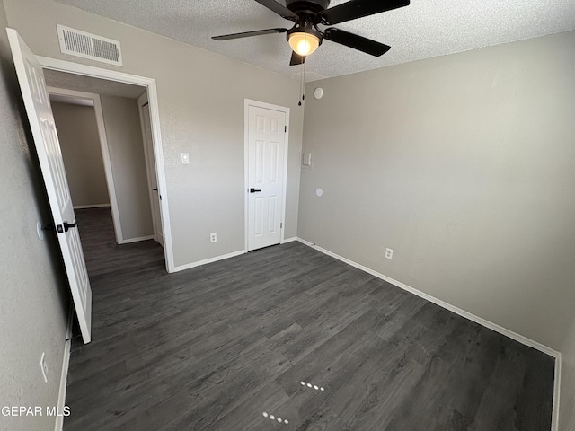 unfurnished bedroom featuring dark wood finished floors, visible vents, ceiling fan, a textured ceiling, and baseboards