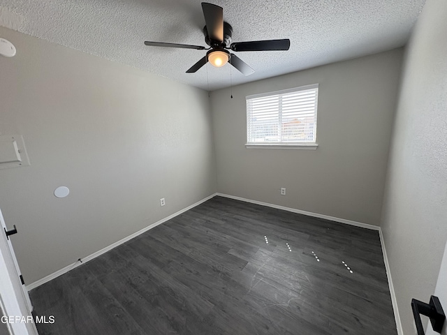 empty room featuring a ceiling fan, dark wood finished floors, a textured ceiling, and baseboards