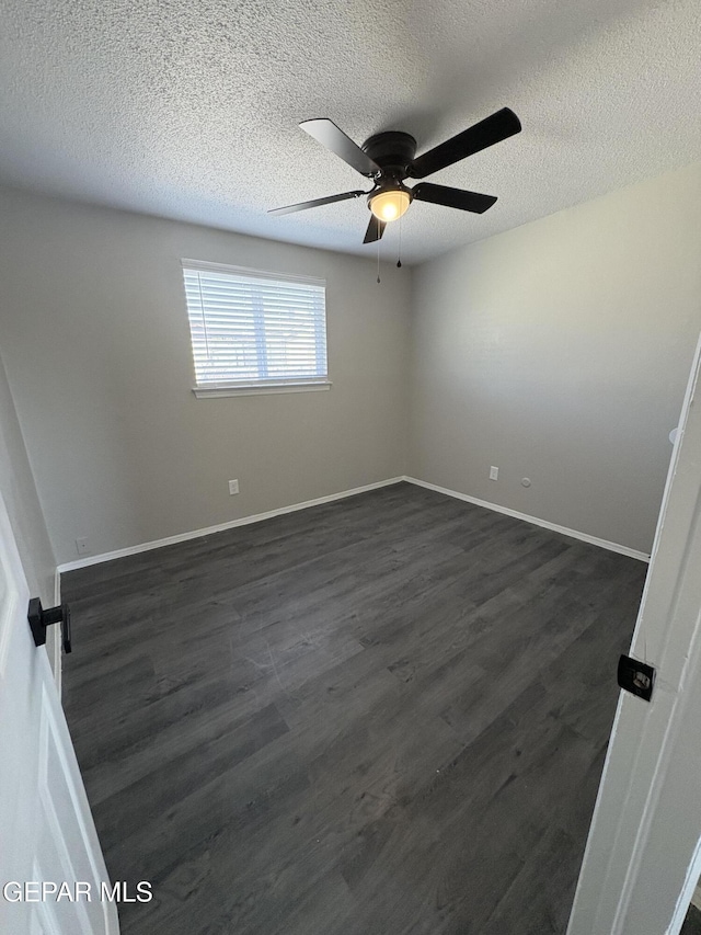 spare room featuring dark wood-style floors, a textured ceiling, baseboards, and a ceiling fan