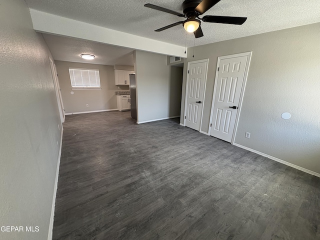 empty room featuring a textured ceiling, dark wood-type flooring, visible vents, and baseboards