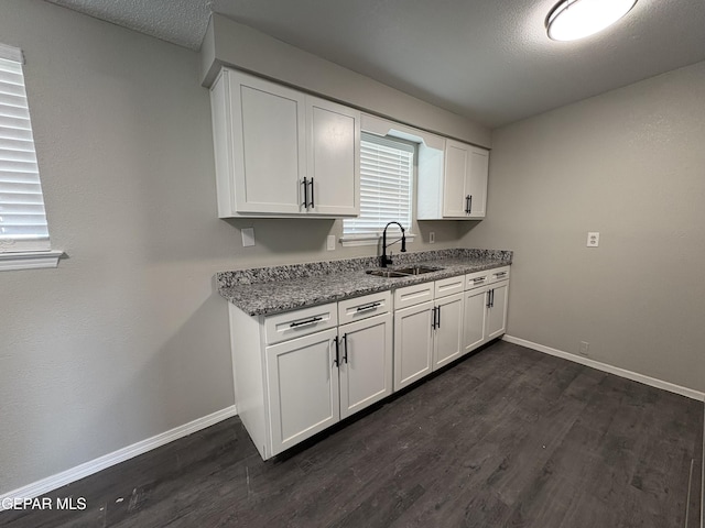 kitchen featuring white cabinets, baseboards, dark wood-style flooring, and a sink