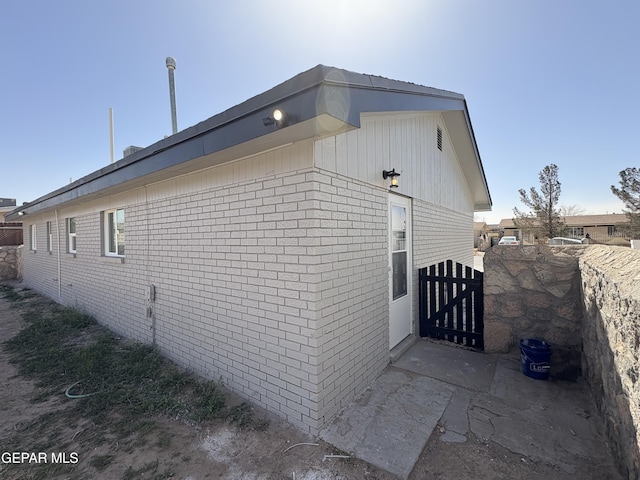 view of side of home with brick siding and fence