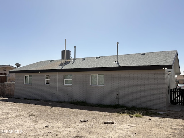 back of house with brick siding and a shingled roof