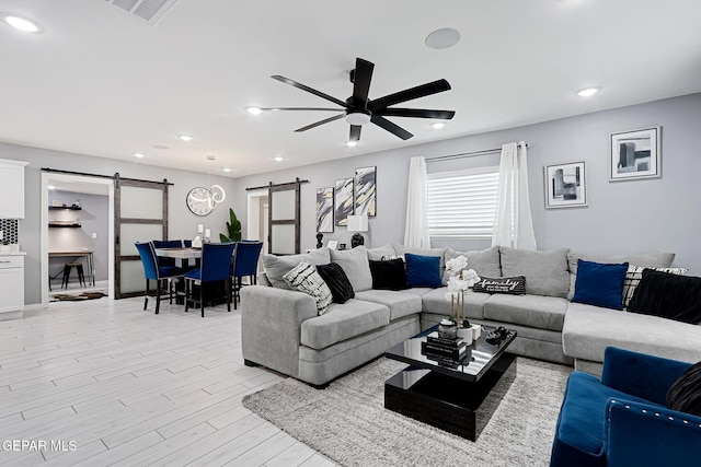 living room with ceiling fan, a barn door, recessed lighting, visible vents, and light wood-style floors