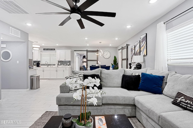 living room featuring a barn door, visible vents, ceiling fan, and recessed lighting