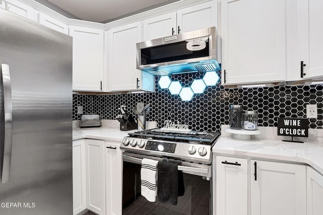 kitchen featuring tasteful backsplash, appliances with stainless steel finishes, white cabinets, and light stone counters