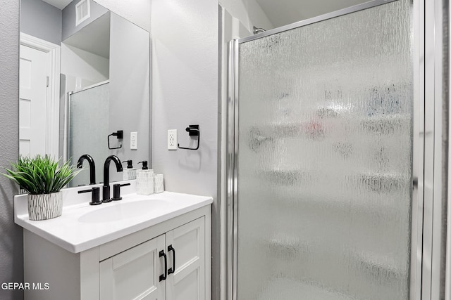 bathroom with a stall shower, visible vents, and vanity