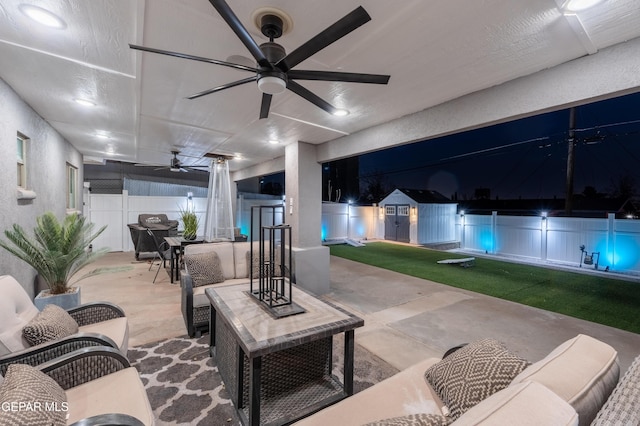 view of patio / terrace featuring a storage shed, a fenced backyard, an outdoor living space, and a ceiling fan