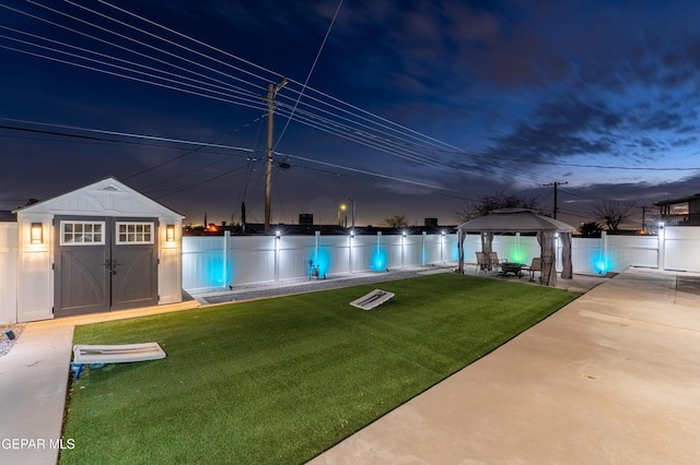 view of swimming pool with a yard, a gazebo, a storage unit, and a fenced backyard