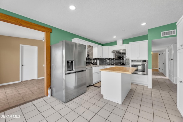 kitchen with stainless steel appliances, light tile patterned flooring, visible vents, and white cabinetry