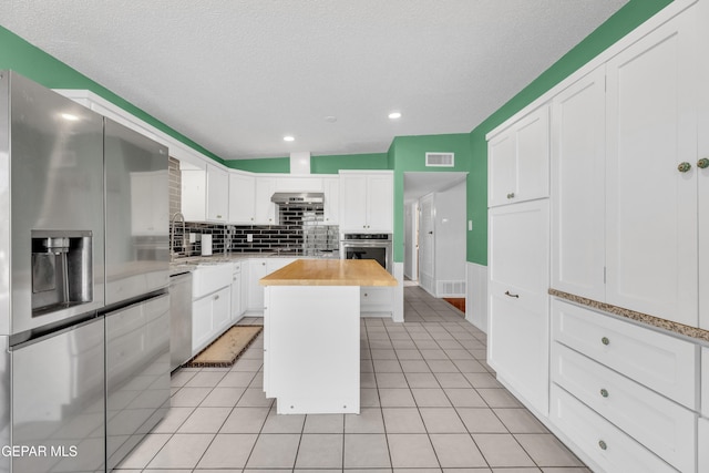 kitchen featuring light tile patterned floors, stainless steel appliances, visible vents, and white cabinets