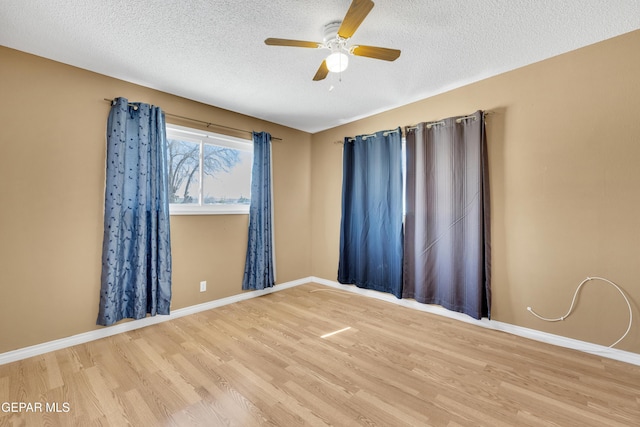 empty room featuring a ceiling fan, a textured ceiling, baseboards, and wood finished floors