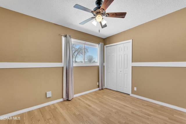 unfurnished bedroom featuring a ceiling fan, a textured ceiling, baseboards, and wood finished floors