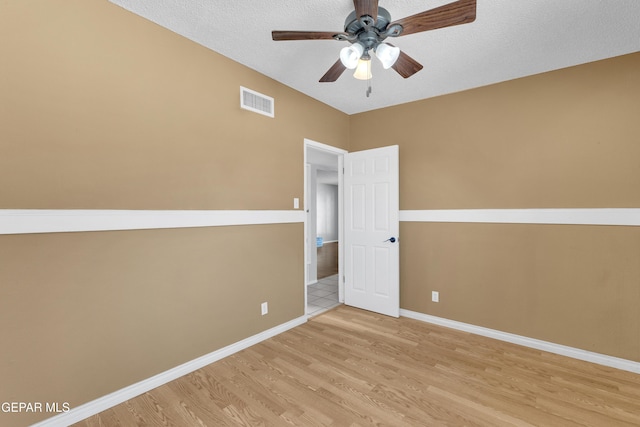 spare room featuring visible vents, ceiling fan, a textured ceiling, wood finished floors, and baseboards