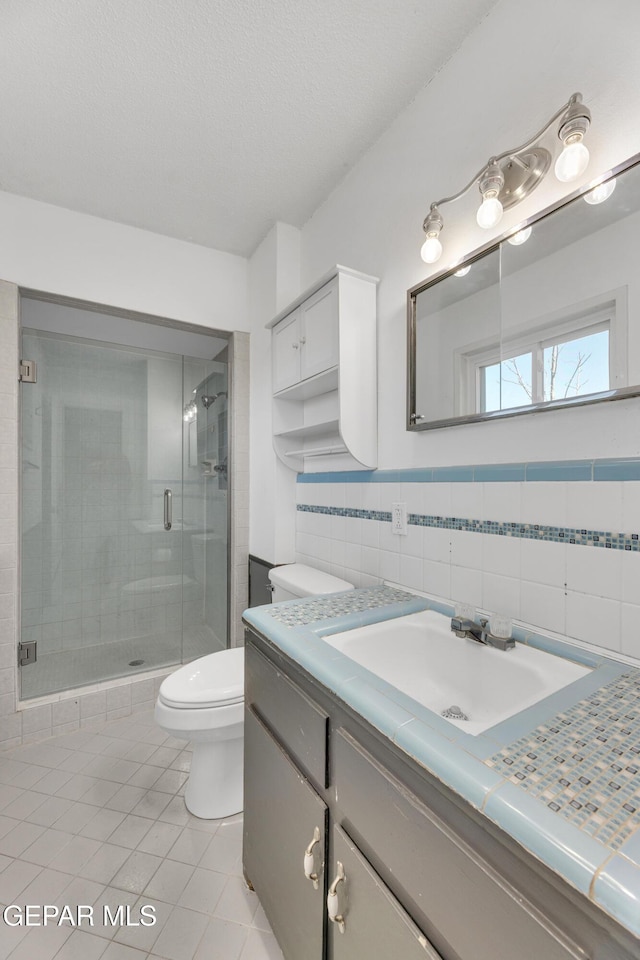 full bath featuring toilet, a textured ceiling, a shower stall, vanity, and tile patterned floors