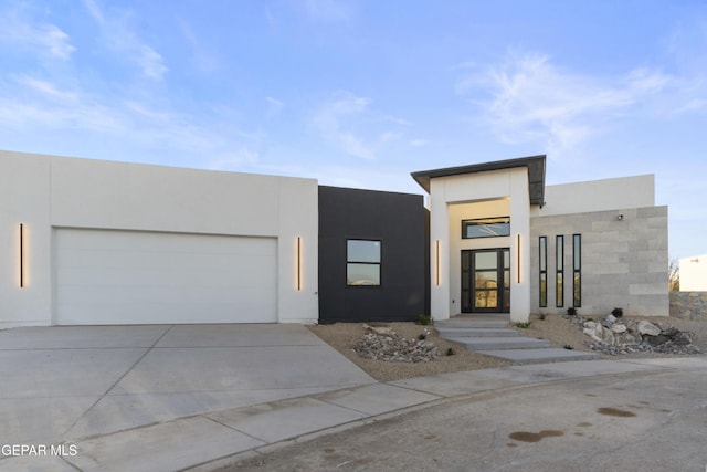 modern home featuring a garage, driveway, and stucco siding