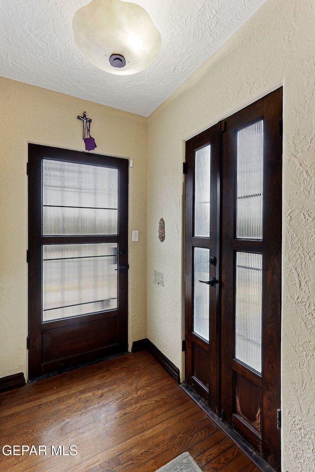 foyer entrance with a textured ceiling, wood finished floors, french doors, and a textured wall