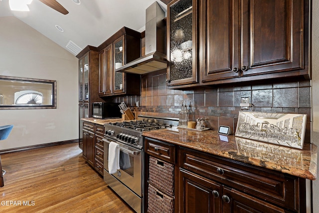 kitchen featuring gas stove, black microwave, dark brown cabinetry, and wall chimney range hood