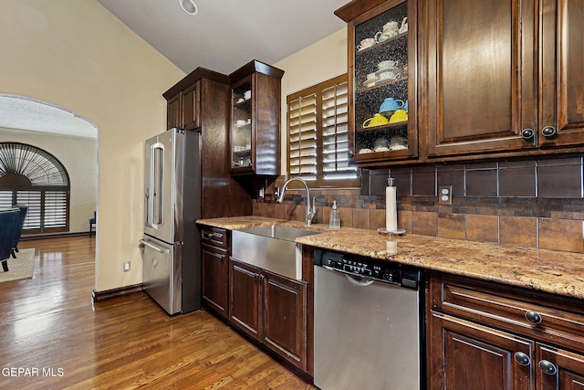 kitchen featuring dark wood-style flooring, tasteful backsplash, appliances with stainless steel finishes, a sink, and dark brown cabinetry